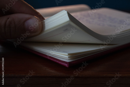 Diario en oficina de casa pasando paginas con la mano indicando los meses actuales en mesa de madera y pared azul 