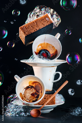 Bubbles and foam, washing dishes concept, balancing porcelain cups with coffee stains and soap bubbles photo