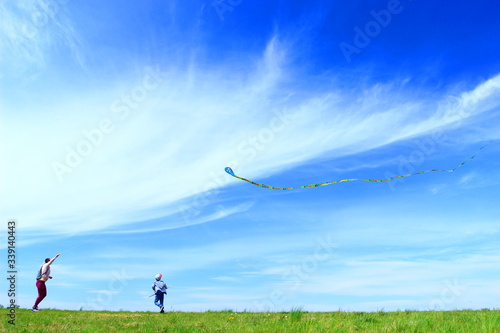 Happy kid and mom playing with kite in beautiful sunny day