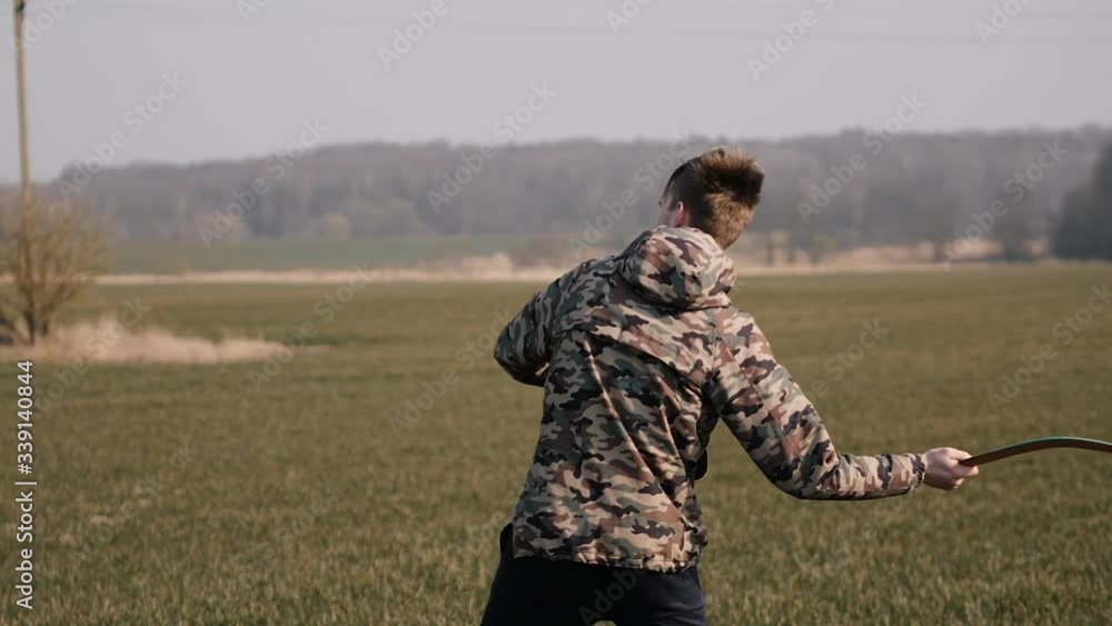 young sports man runs in the field and launches a boomerang into the sky