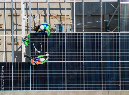 Photos top view worker installing a solar cell on the factory roof.