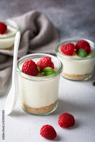 cheesecake in a glass decorated with raspberries and mint on a gray background