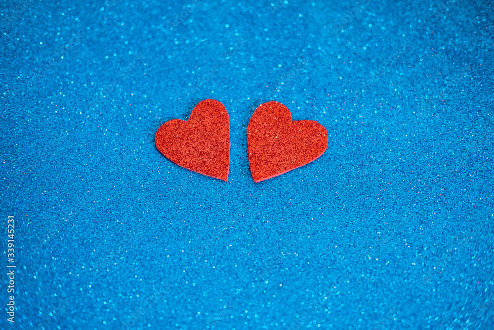 Obraz premium Two red glitter hearts on shiny blue background