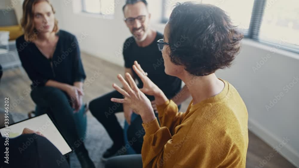 Businesswoman talking during team-building seminar in office. Corporate professionals engaged in personal development training program.
