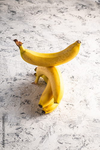 Stacked banana fruits on white textured background, angle view copy space
