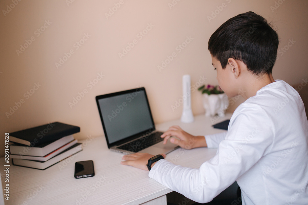 Schoolboy play online games at home while study on quarantine. Mockup of laptop Schoolboy play online games at home while study on quarantine. Mockup of laptop