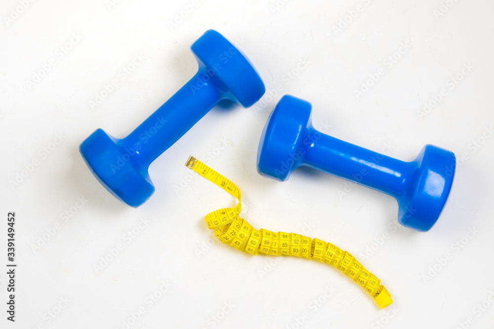 dumbbell and centimeter on a light background dumbbell and centimeter on a light background