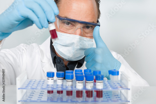 scientist works with medical gloves and medical face mask with blood samples for virus testing in a tube rack shows thumbs up