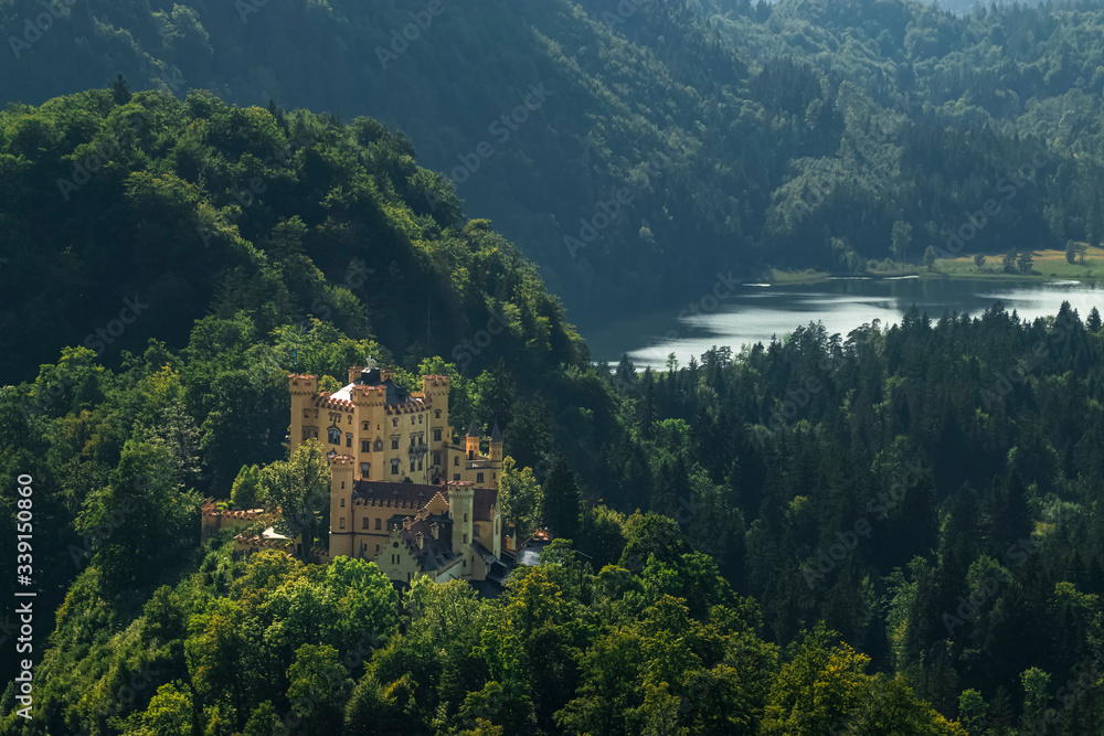 View of the fairy-tale castle with a yellow facade from Hohenschwangau in the middle of the Alps. Photograph taken in Schwangau, Bavaria, Germany.