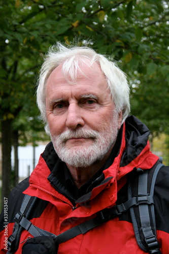 Portrait of a white bearded sprightly senior in red black colored active hiking outfit © Sahara Frost