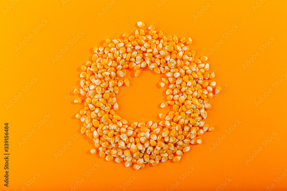 Yellow dried grain corn isolated on orange background, for popcorn, top view, concept photo Yellow dried grain corn isolated on orange background, for popcorn, top view, concept photo