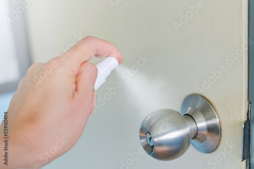 Cleaning door knob,Spraying alcohol on the doorknob. Before opening the door with alcohol spray for Coronavirus prevention ,Hand sanitizer