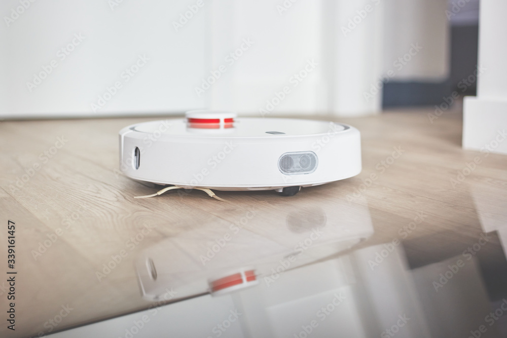 robotic vacuum cleaner on a laminated wooden floor Charging dock station Concept - Robot vacuum cleaner in the loft interior style close-up robotic vacuum cleaner on a laminated wooden floor Charging dock station Concept - Robot vacuum cleaner in the loft interior style close-up