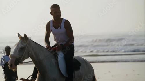 An exotic man riding a horse in front off the ocean
