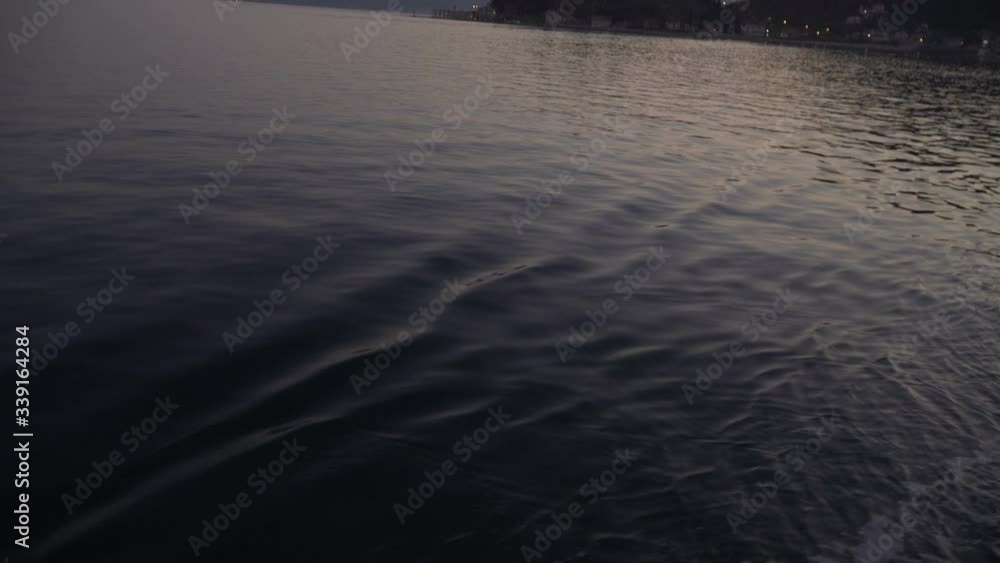 Water trail foaming behind a ferry boat. Travelling by ferry at evening, sunset light reflection, houses at sea coast, 4k Water trail foaming behind a ferry boat. Travelling by ferry at evening, sunset light reflection, houses at sea coast, 4k