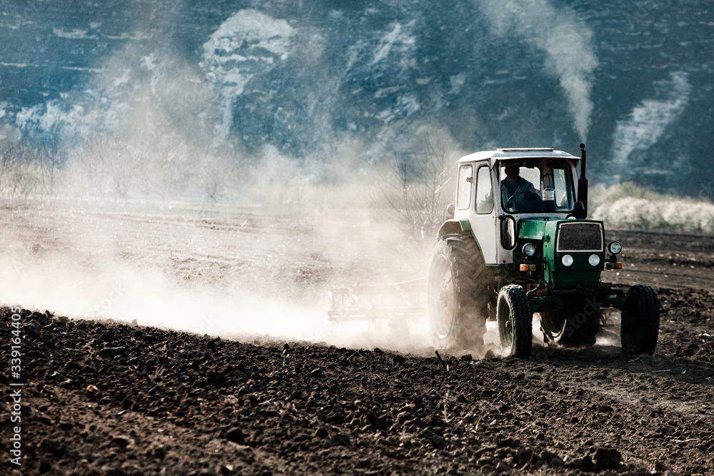 Fototapeta premium Farmer in tractor preparing land. Agricultural works at farmlands. agricultural work plowing land on a tractor. Tractor on a farmer field in Moldova, Europe.