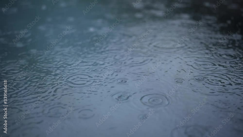 Slowmotion of raindrops falling on blue water Slowmotion of raindrops falling on blue water