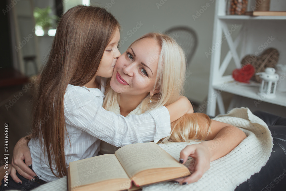 Mom and daughter read a book at home. Mom and daughter read a book at home.