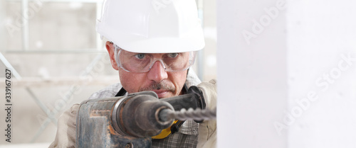 Foto man using an electric pneumatic drill making a hole in wall, professional construction worker with safety hard hat,, gloves and protective glasses