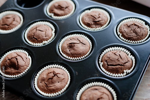 Chocolate cupcakes. Homemade chocolate muffins. The process of making homemade chocolate cupcakes with whipped cream and decorated with chocolate and raspberry pieces.