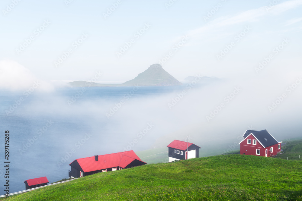 Foggy morning view of a houses with red roof in the Velbastadur village on Streymoy island, Faroe islands, Denmark. Landscape photography