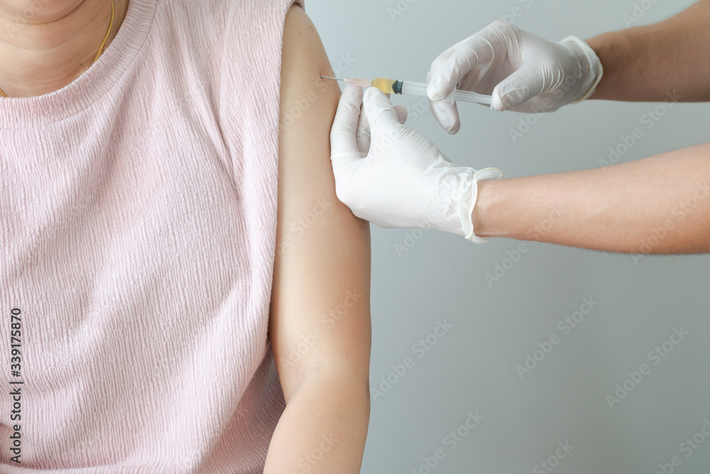 The doctor is injecting medicine for treatment or a vaccine to prevent corona virus or Covid 19 in the arms of an Asian woman The doctor is injecting medicine for treatment or a vaccine to prevent corona virus or Covid 19 in the arms of an Asian woman