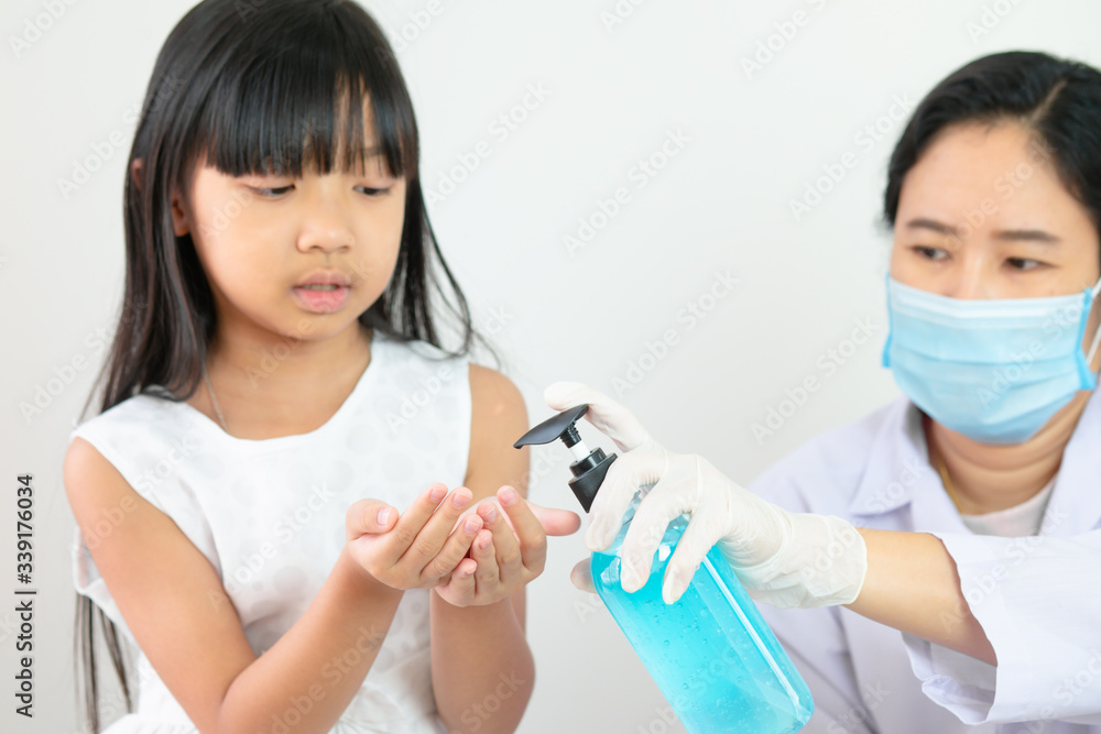 Asian nurse or doctor or medical assistant is pressing a bottle of alcohol cleanser for the girl with selective focus on hand. Asian nurse or doctor or medical assistant is pressing a bottle of alcohol cleanser for the girl with selective focus on hand.