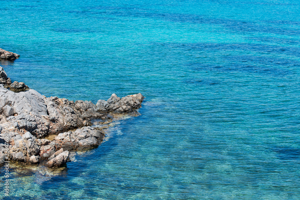 Closeup of vibrant blue waters and rocky coastline at Agia Dynami beach.
