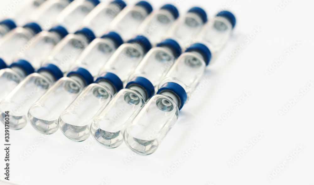 Glass medicine bottles with injection fluid with blue aluminium caps for vaccination. Cancer, coronavirus covid-2019, painand diabetes treatment, pharmaceutical medicine concept. Glass medicine bottles with injection fluid with blue aluminium caps for vaccination. Cancer, coronavirus covid-2019, painand diabetes treatment, pharmaceutical medicine concept.