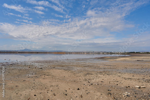 Beautiful panoramic view from the shore of the salty lake Larnaca with blue sky and small clouds, reflections in the water, Larnaca, island Cyprus, deserted landscape
