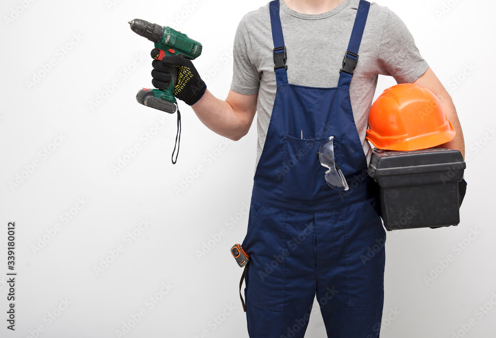 The worker in professional uniform with toolbox in hand on the gray background The worker in professional uniform with toolbox in hand on the gray background