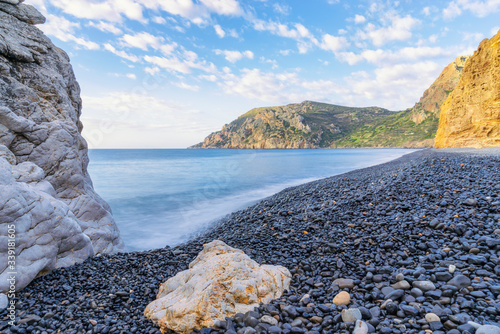Fototapeta Naklejka Na Ścianę i Meble -  Black volcanic pebbles on a beach in the Greek islands.