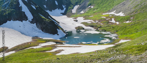 Mountain lake among snow, spring in the mountains, panoramic image