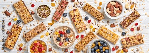 Cereal healthy snack. Granola bar with nuts and dry fruit berries. Diet food. Protein muesli bars isolated on wood background. Sport oatmeal bar, top view, closeup, banner