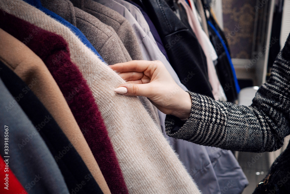 woman's hand on the background of a collection of clothes in the store