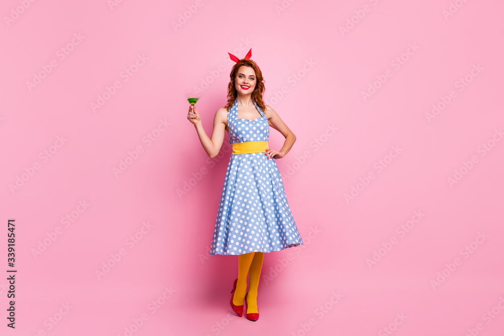 Cheers guys. Full body photo of pretty stunning lady holding green cocktail glass theme retro party wear headband dotted dress red stilettos yellow tights isolated pink color background