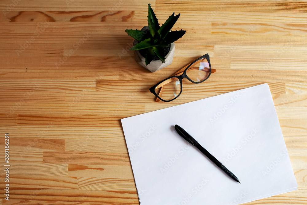 wooden table with blank white paper and pen and glasses and notebook and plant. workplace. business. wooden table with blank white paper and pen and glasses and notebook and plant. workplace. business.