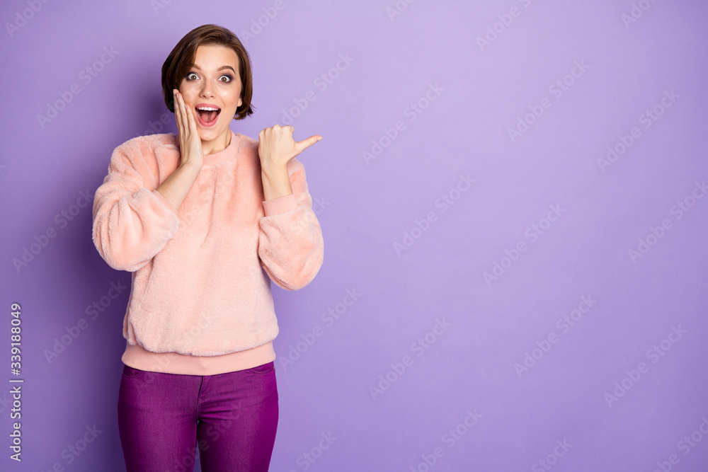 Fototapeta premium Portrait of impressed funky crazy girl promoter point thumb copyspace indicate incredible discounts promotion ads suggest select adverts wear pastel sweater isolated violet color background