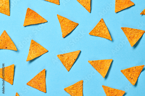 Nachos Mexican chips colorful pattern on blue background. Tortilla nacho chip closeup, fashionable trendy flat lay. Crisps nachos snack wallpaper, top view. Creative concept