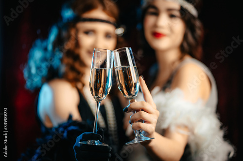 Beautiful flappers women dressed in style of Roaring twenties drinking champagne. Vintage, retro party, fashion, girls friends concept photo
