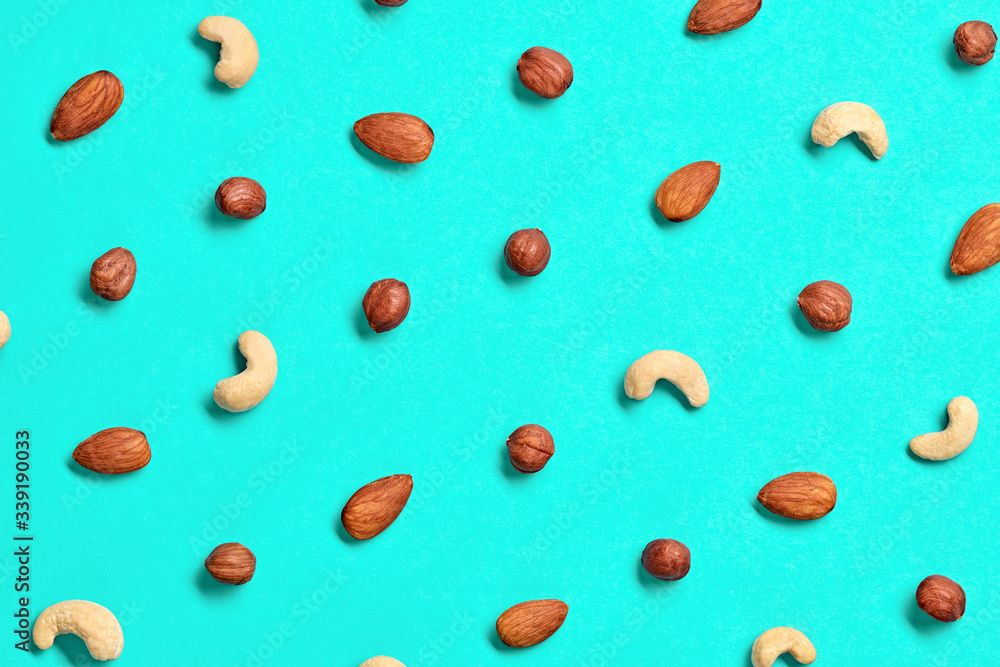 Nuts mix colorful pattern on blue background. Fitness diet super food. Almonds, hazelnuts, cashews wallpaper, top view. Creative concept closeup, fashionable trendy nuts flat lay