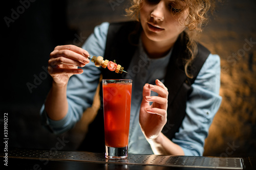 close-up of female barman carefully decorates cocktail Bloody Mary by canapes.