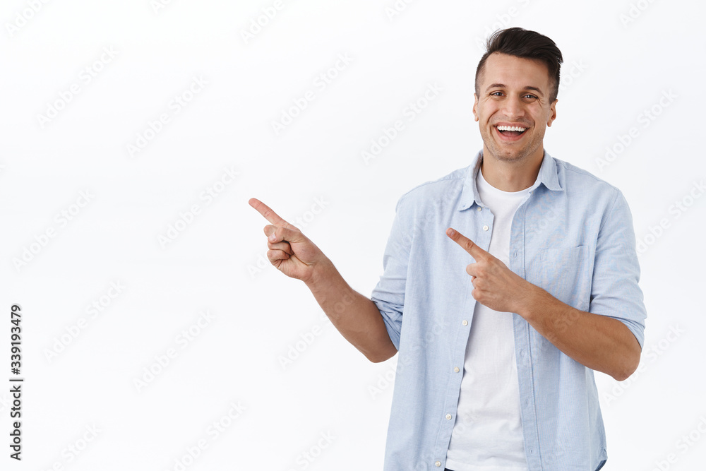 Portrait of handsome cheerful guy, smiling broadly as advertising product, pointing fingers left and laughing, recommend visit store, go click link, promote company banner, white background Portrait of handsome cheerful guy, smiling broadly as advertising product, pointing fingers left and laughing, recommend visit store, go click link, promote company banner, white background