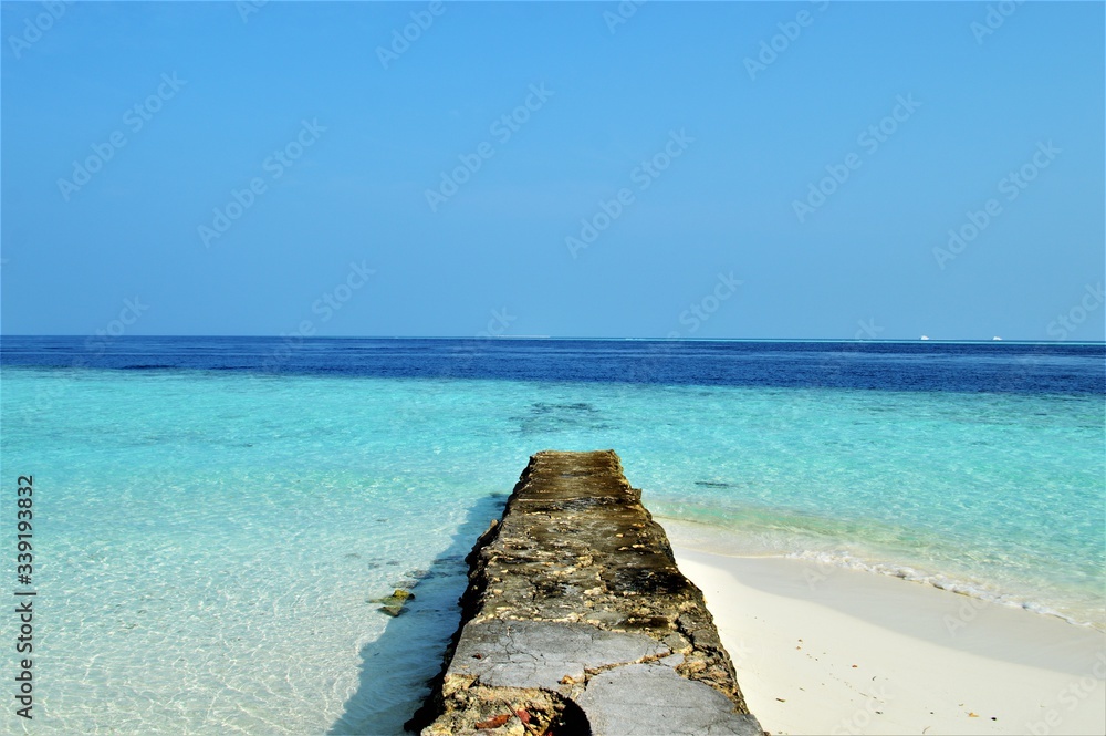 The stone pier on the island of Maldives, beautiful view of crystal clear water and blue sky
