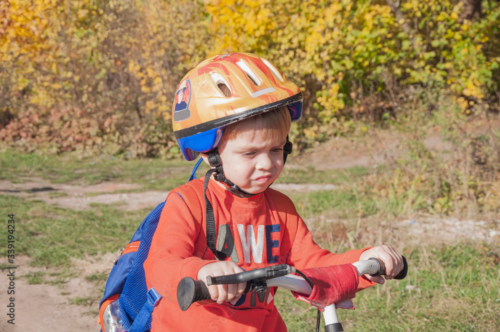 A boy in a helmet with a backpack rides a bicycle. Walk in the park. A boy in a helmet with a backpack rides a bicycle. Walk in the park.