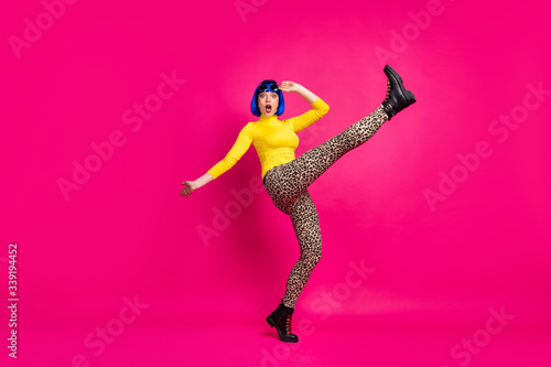 Full body profile photo of terrified lady raise leg up falling down slippery road wear retro specs yellow turtleneck blue wig boots leopard trousers isolated bright pink color background