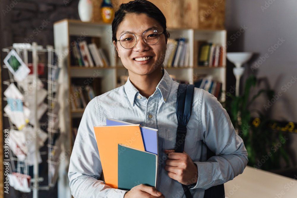 Image of happy asian man smiling and holding exercise books Image of happy asian man smiling and holding exercise books