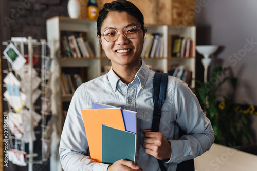 Image of happy asian man smiling and holding exercise books