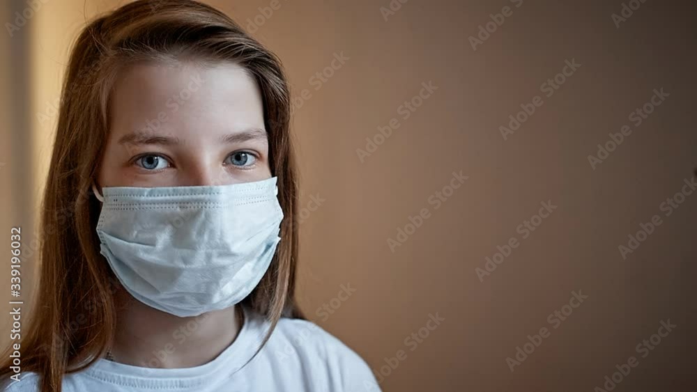children sit at home in quarantine and look out the window, two girls on the windowsill in medical masks children sit at home in quarantine and look out the window, two girls on the windowsill in medical masks