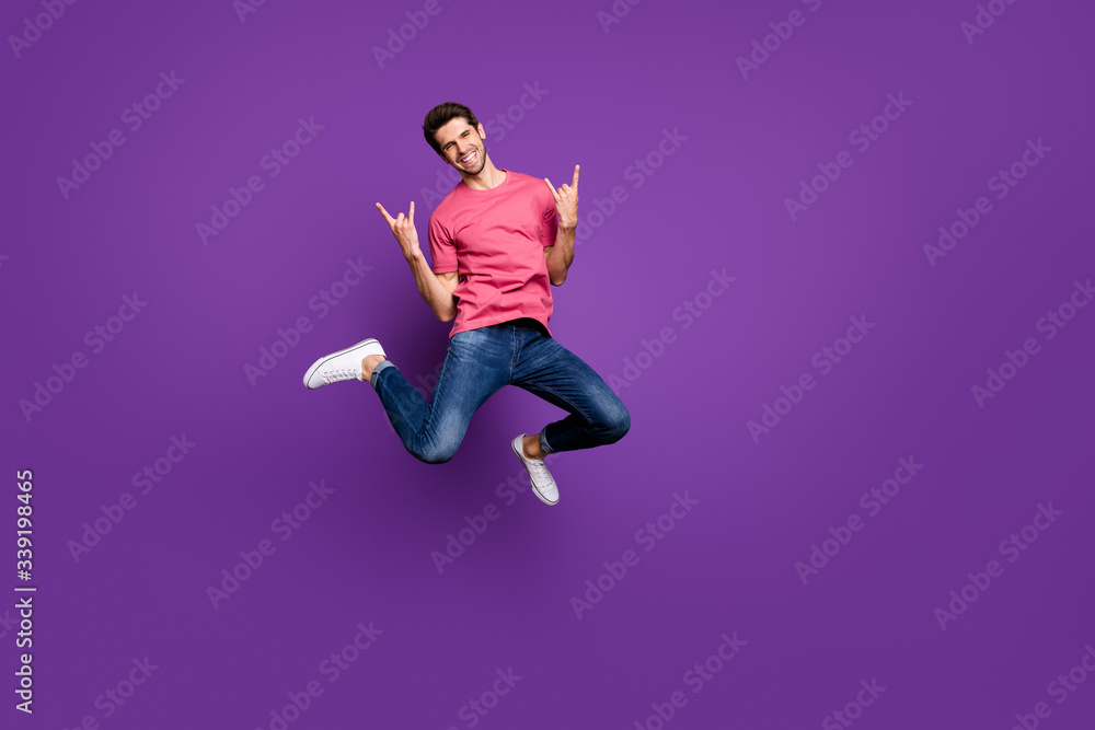 Full size photo of cheerful crazy guy heavy metal music concert lover enjoy rejoice jump show horned symbol wear casual style clothes sneakers isolated over bright shine color background Full size photo of cheerful crazy guy heavy metal music concert lover enjoy rejoice jump show horned symbol wear casual style clothes sneakers isolated over bright shine color background